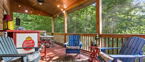 A covered outdoor area with a wooden ceiling, a sign reading 'Welcome to our porch,' and a view of a forest.