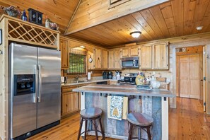 Una cocina con gabinetes de madera, electrodomésticos de acero inoxidable y una barra con taburetes.