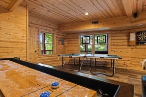 Una habitación con paredes de madera, una mesa de ping pong y un dardo.
