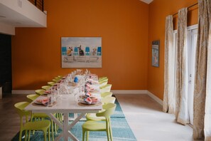 A dining area with a long table set for a meal, chairs, and a painting on the wall. - Sleeps 20 Games Basketball Pool Movie Room (Bradenton)