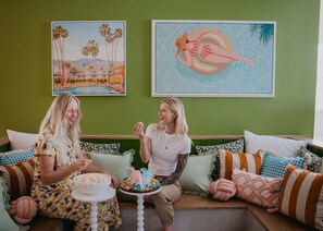 Två personer sitter i en soffa med en skål popcorn och en tallrik med färgglada snacks.