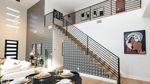 Ein modernes Interieur mit Essbereich, Treppe und Kunstwerken.
