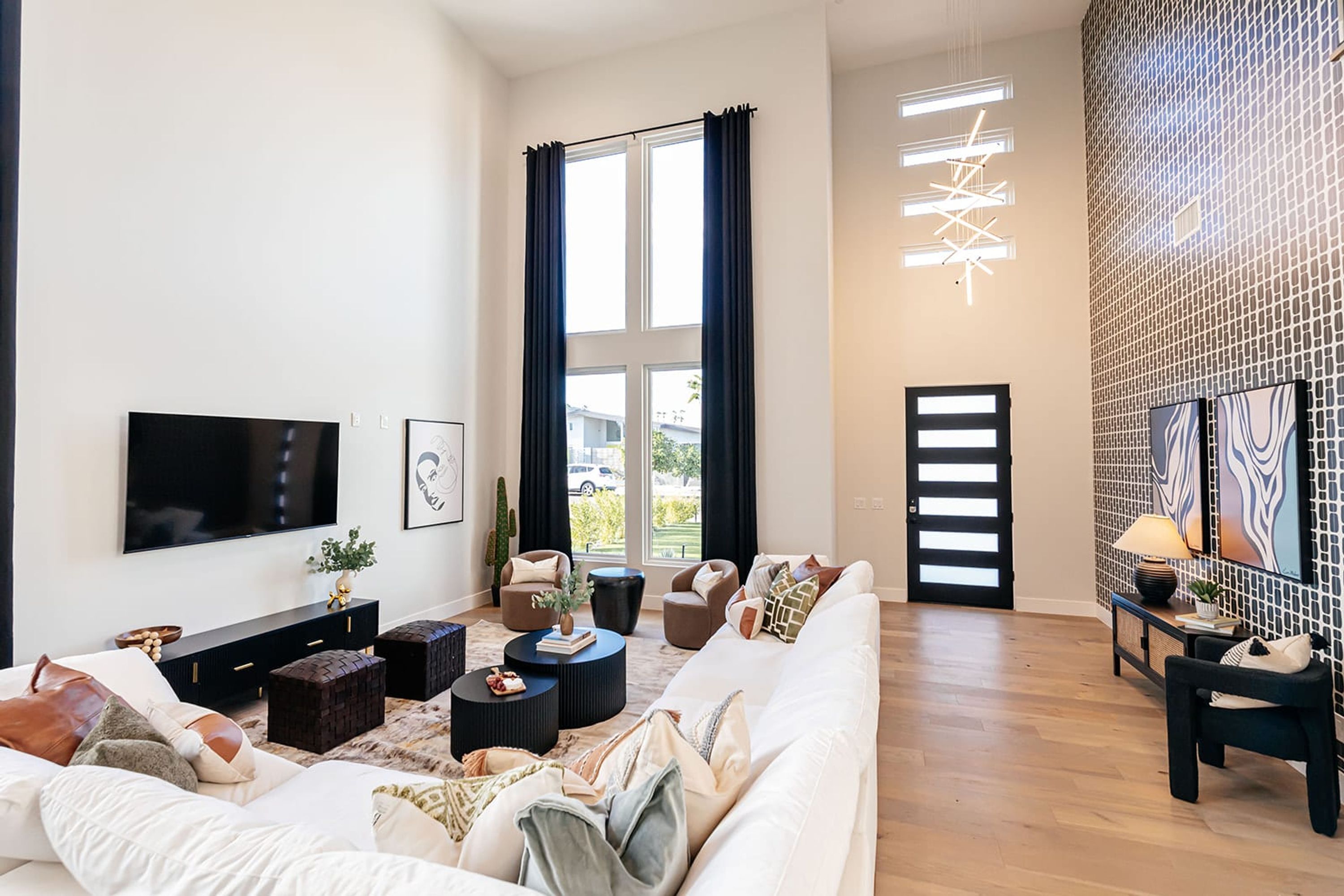 A modern living room with a large flat-screen TV, a sofa, a coffee table, and a patterned wall.