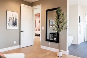 A hallway with a door leading to a bedroom, a large mirror, and a potted plant. - A Desert Dream Perfect Getaway in Old Town (Scottsdale)