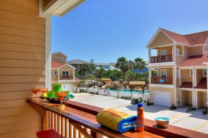 A residential area with a swimming pool, multiple houses, and a wooden deck with items like a towel and a bottle. - Borracho Beach- Waterslide Pet Friendly (Port Aransas)