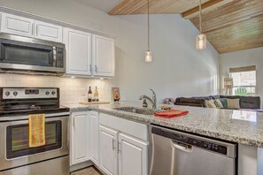 A kitchen with white cabinets, stainless steel appliances, and a granite countertop. - Borracho Beach- Waterslide Pet Friendly (Port Aransas)