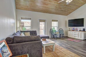 A living room with a sofa, a coffee table, a TV, and a dining area with chairs. - Borracho Beach- Waterslide Pet Friendly (Port Aransas)