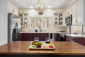 A modern kitchen with a wooden island, stainless steel appliances, and a view of trees through the window. - 7k Sqft Estate - Epic Amenities Fun - Sleeps 20 (Asheville)