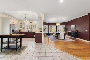 A spacious kitchen with a dining area, wooden flooring, and a view through the windows. - 7k Sqft Estate - Epic Amenities Fun - Sleeps 20 (Asheville)