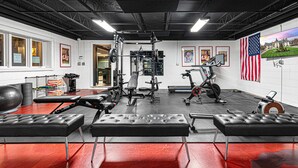 Una palestra con diverse attrezzature per esercizi, tra cui una panca per pesi e un tapis roulant, e una bandiera americana.