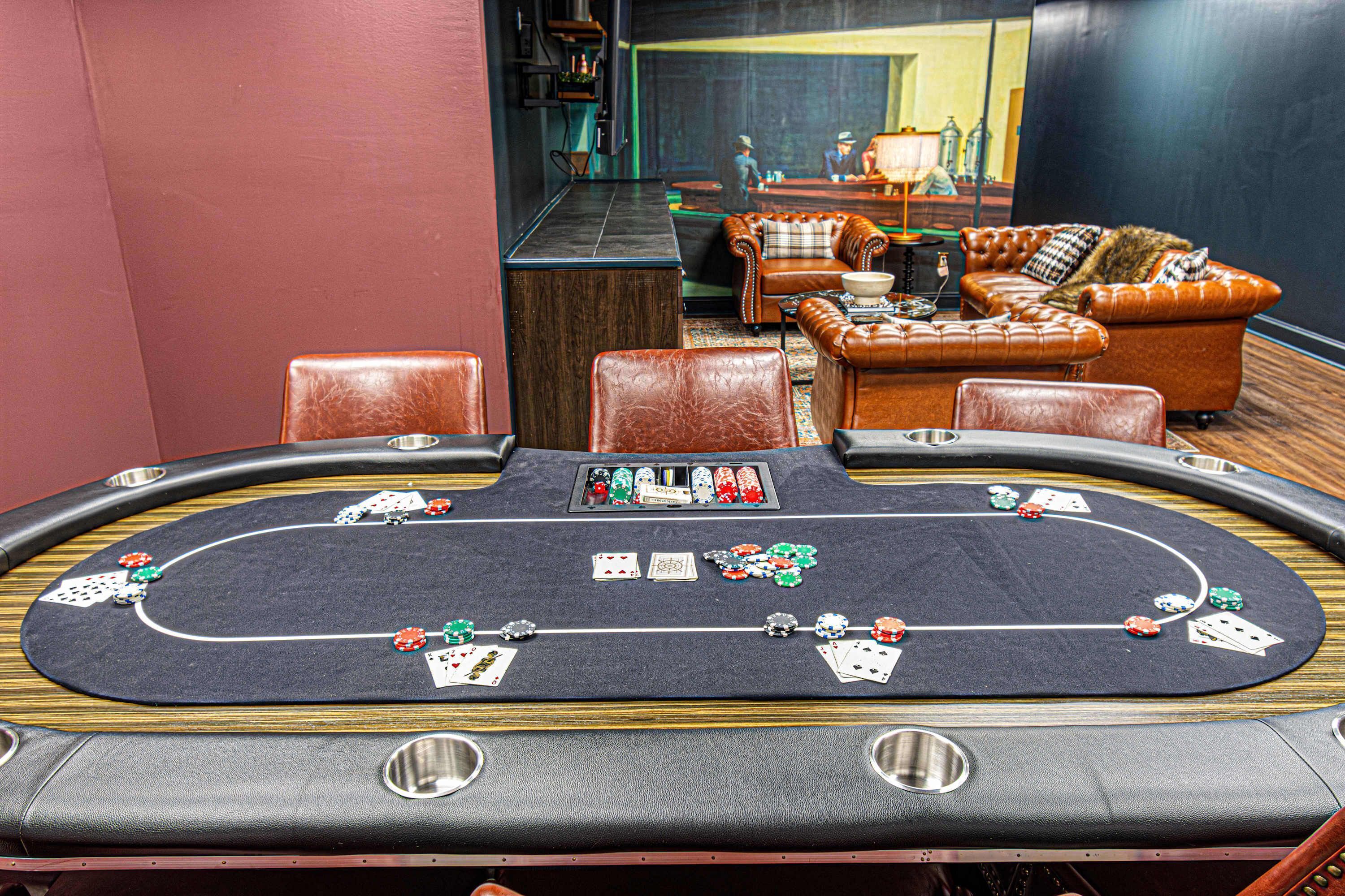 A casino table with poker chips and cards, leather chairs, and a sofa in the background.