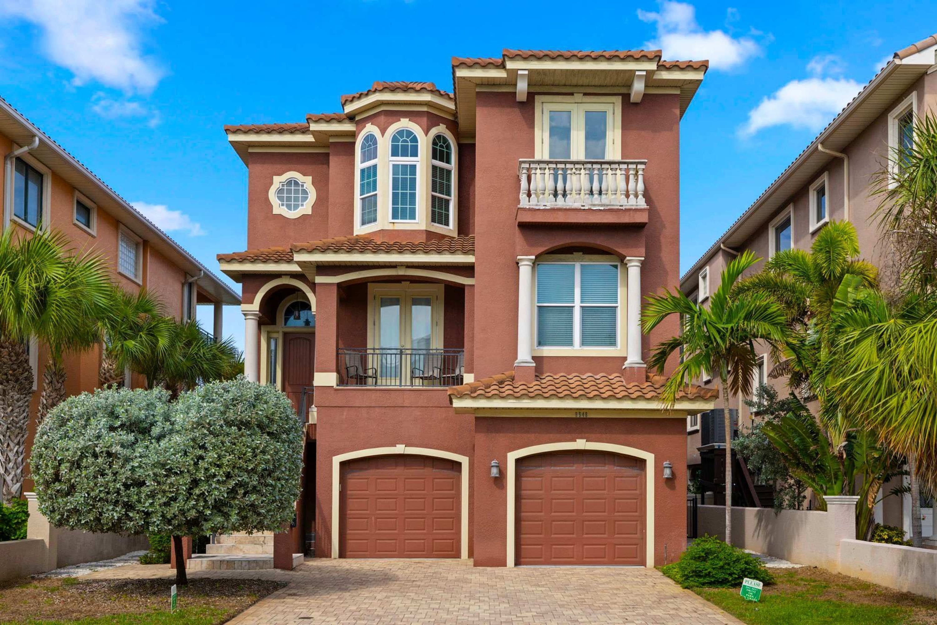 A two-story house with a red facade, a balcony, and a garage.