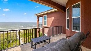 Un balcone con vista sull'oceano, un divano, un tavolino e una finestra.