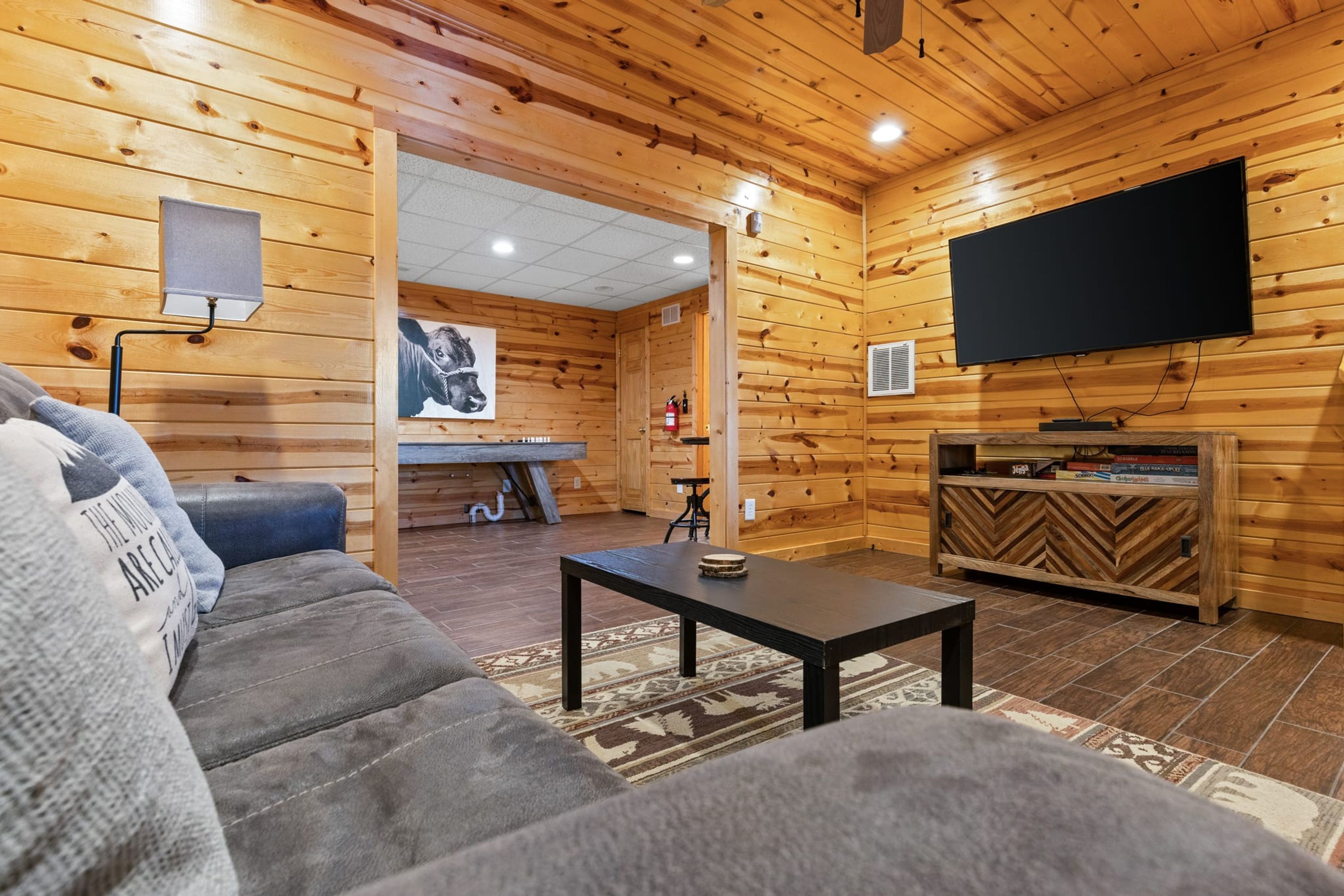 L’intérieur chaleureux d’un chalet en bois comprend un canapé, une table basse, un téléviseur à écran plat et une cheminée.