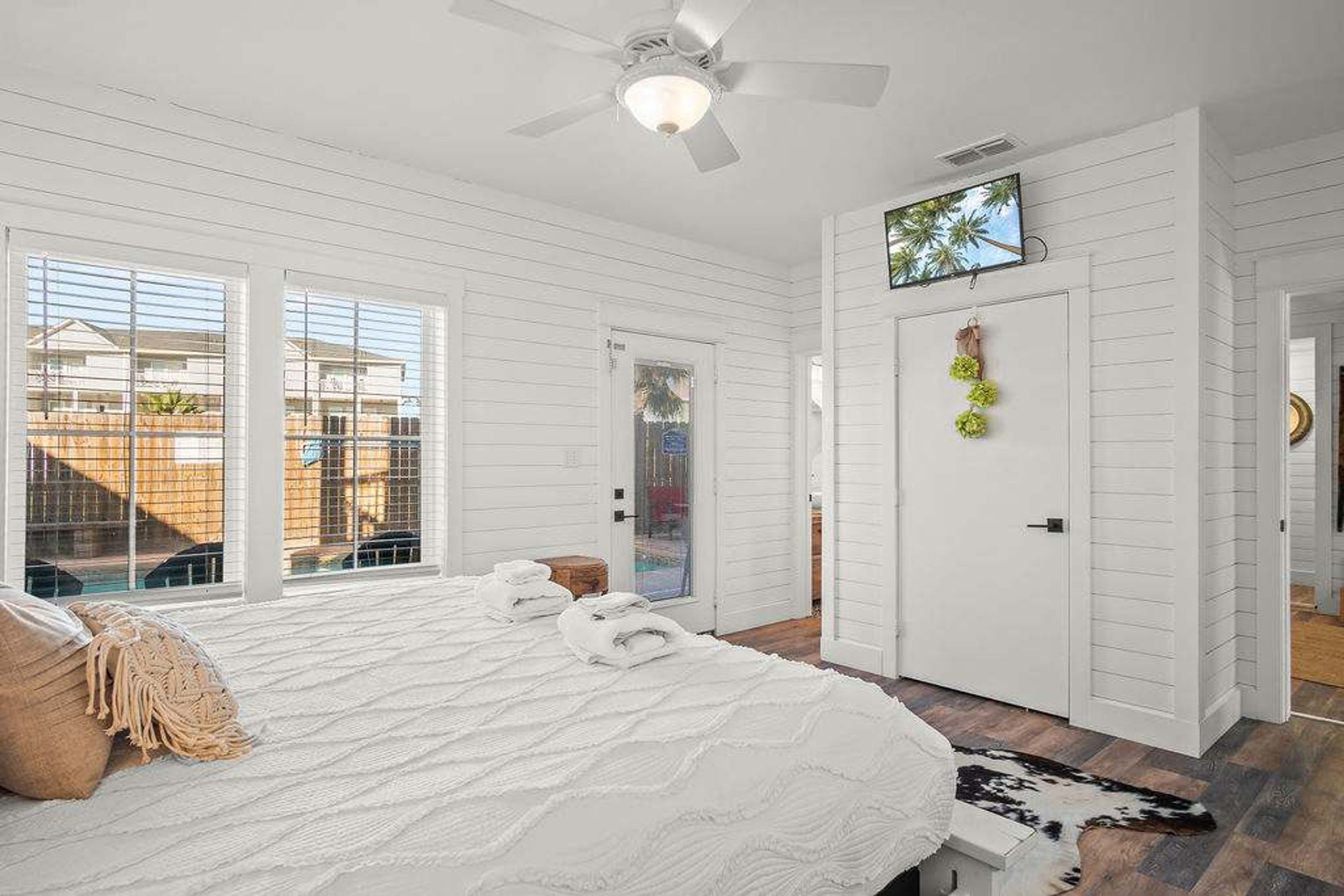 Une chambre à coucher avec un lit, un ventilateur de plafond, une télévision et une porte donnant sur l’extérieur.