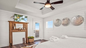 Ein Schlafzimmer mit Bett, Deckenventilator, Holztür, Fenster und Wanddekorationen.