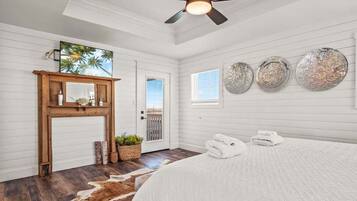 A bedroom with a bed, a ceiling fan, a wooden door, a window, and wall decorations.