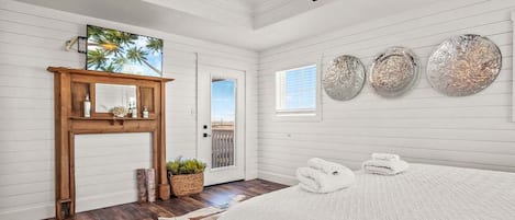 A bedroom with a bed, a ceiling fan, a wooden door, a window, and wall decorations.