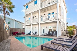 A multi-story building with a swimming pool, outdoor seating, and a wooden deck. - Island Star 5 Br Home Private Pool Boardwalk (Port Aransas)