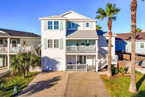 A two-story residential building with a front porch, a balcony, and a garage. - Island Star 5 Br Home Private Pool Boardwalk (Port Aransas)
