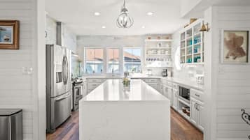 Una cocina moderna con una isla central, electrodomésticos de acero inoxidable y un amplio ventanal que proporciona luz natural.