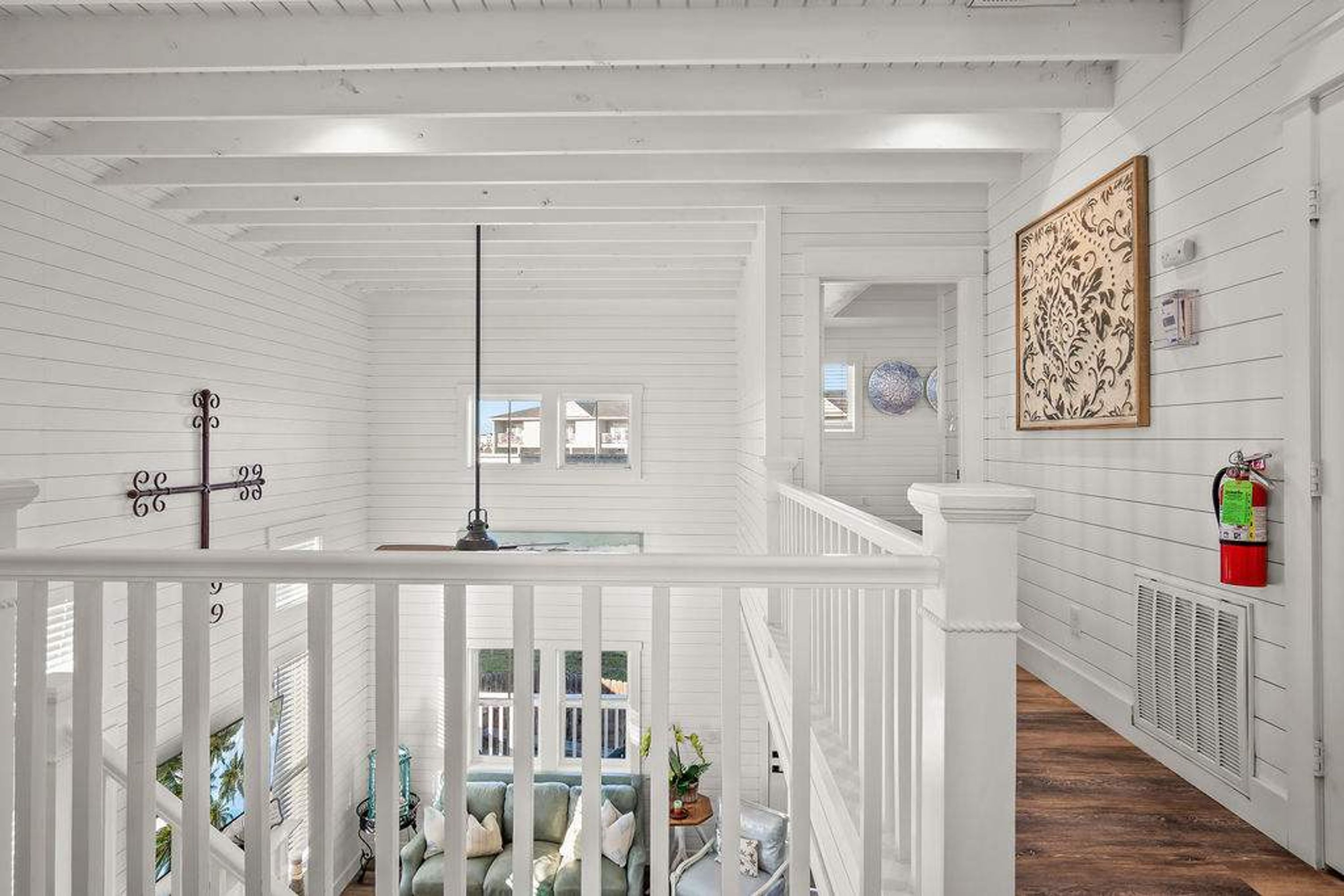 A white wooden interior with a staircase, a fire extinguisher, and a decorative wall piece.