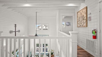 A white wooden interior with a staircase, a fire extinguisher, and a decorative wall piece.