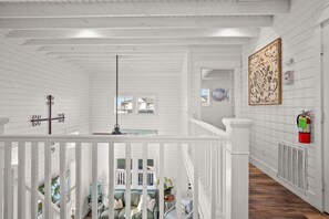 Un interior de madera blanca con una escalera, un extintor y un elemento decorativo en la pared.
