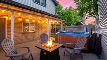 A backyard with a hot tub, a fire pit, and outdoor seating.