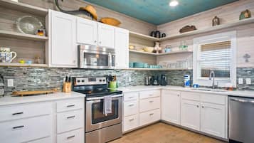 A modern kitchen with white cabinetry, a stainless steel oven, and a built-in microwave.