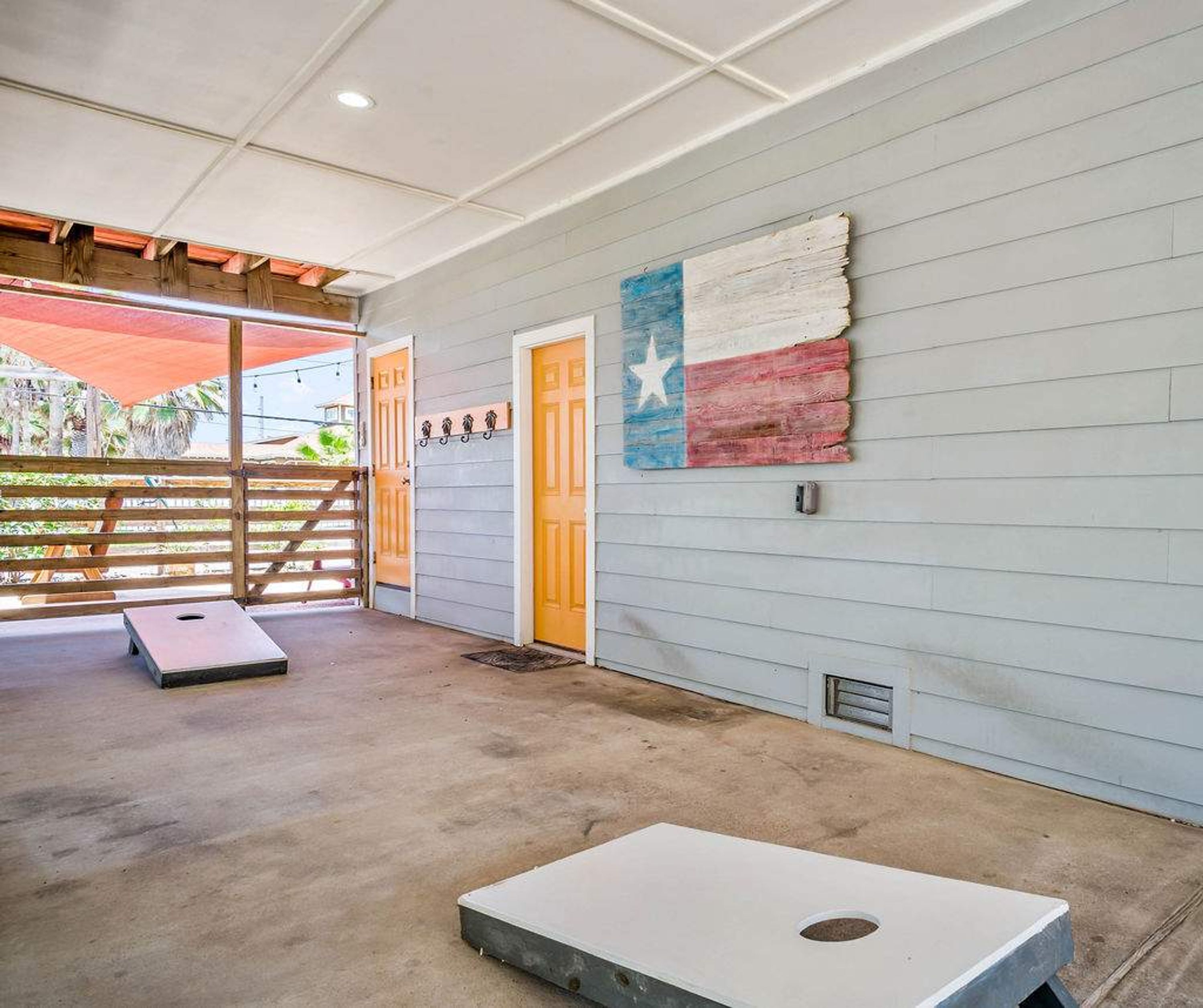 A room with a concrete floor, a wooden door, and a wall with a Texas flag mural.