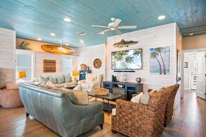 A living room with a sofa, armchairs, a coffee table, and a ceiling fan. - Sea Gypsy Fire Pit Community Pool Corn Hole (Port Aransas)