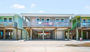 A multi-story building with a covered entrance and a balcony. - Sea Gypsy Fire Pit Community Pool Corn Hole (Port Aransas)