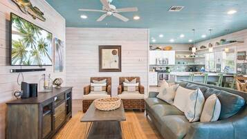 A modern living room with a sofa, chairs, a coffee table, and a TV.