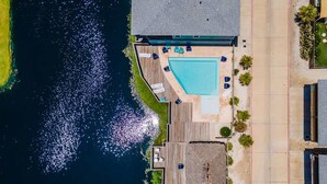 A swimming pool with a deck, surrounded by a wooden deck area with lounge chairs. - Sea Gypsy Fire Pit Community Pool Corn Hole (Port Aransas)