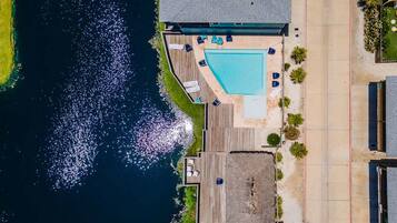 A swimming pool with a deck, surrounded by a wooden deck area with lounge chairs.