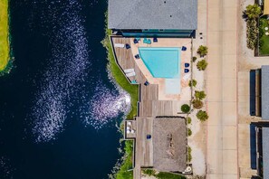 A swimming pool with a deck, surrounded by a wooden deck area with lounge chairs. - Sea Gypsy Fire Pit Community Pool Corn Hole (Port Aransas)