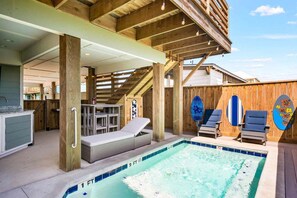 Ein Poolbereich mit Liegestuhl, einem kleinen Tisch und einer Holzterrasse.