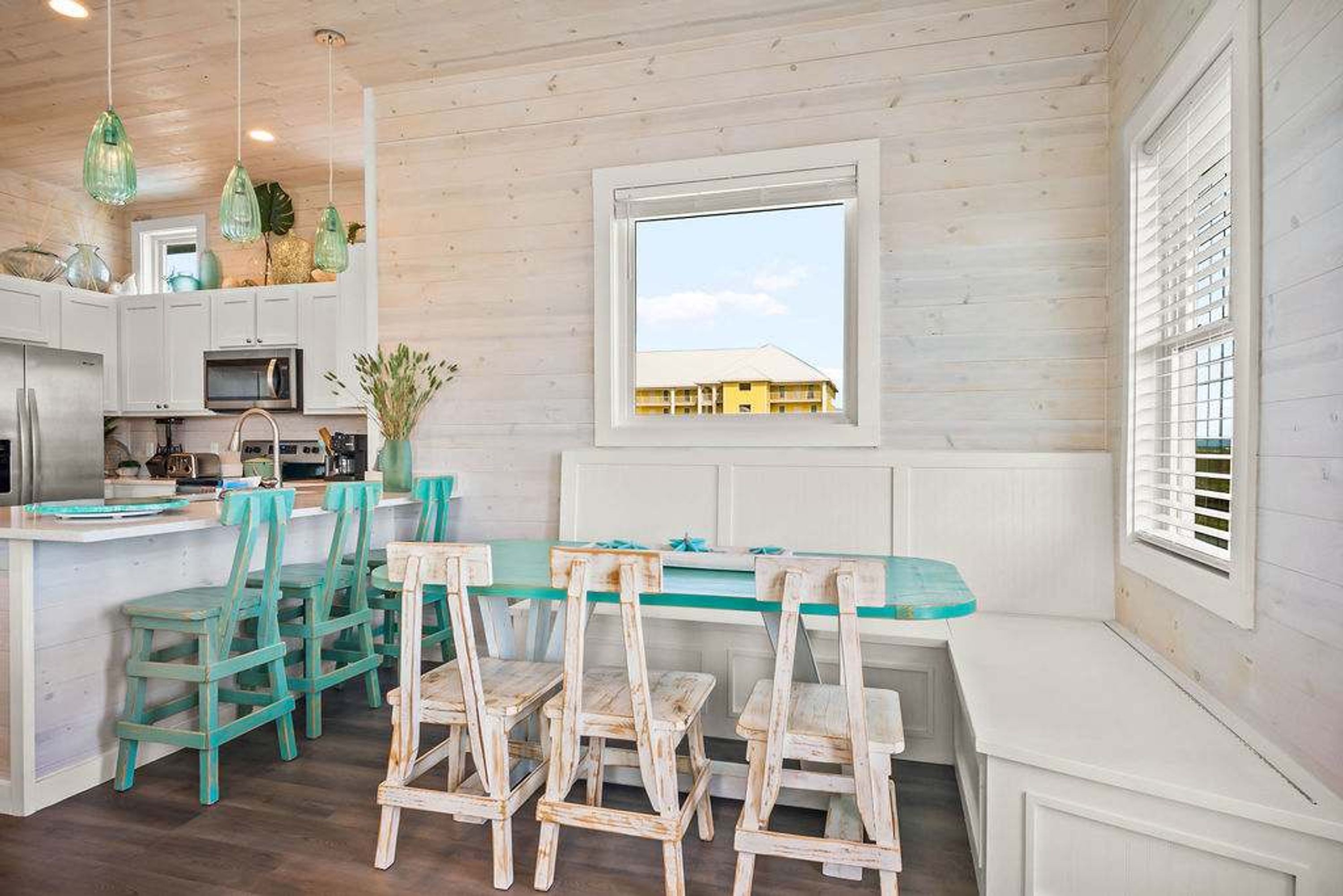 A kitchen with a central island, white cabinetry, and a view of a building through a window.
