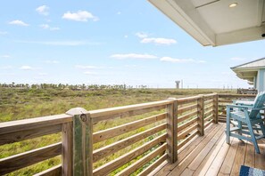 Eine Holzterrasse mit Blick auf eine grüne Landschaft und ein Gebäude in der Ferne.