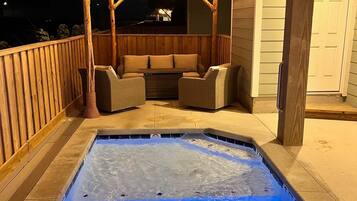 An outdoor hot tub area with seating and string lights.