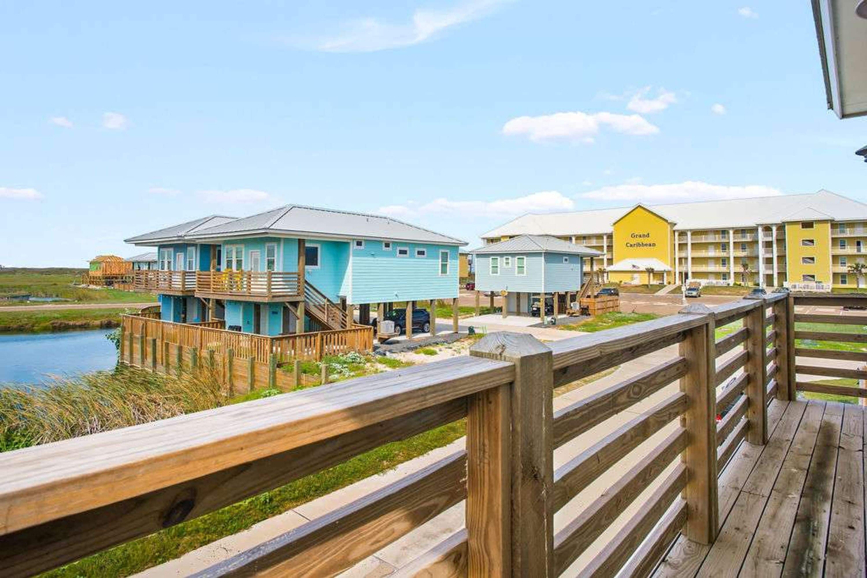 A coastal hotel with multiple-story buildings, a wooden deck, and a view of the water.