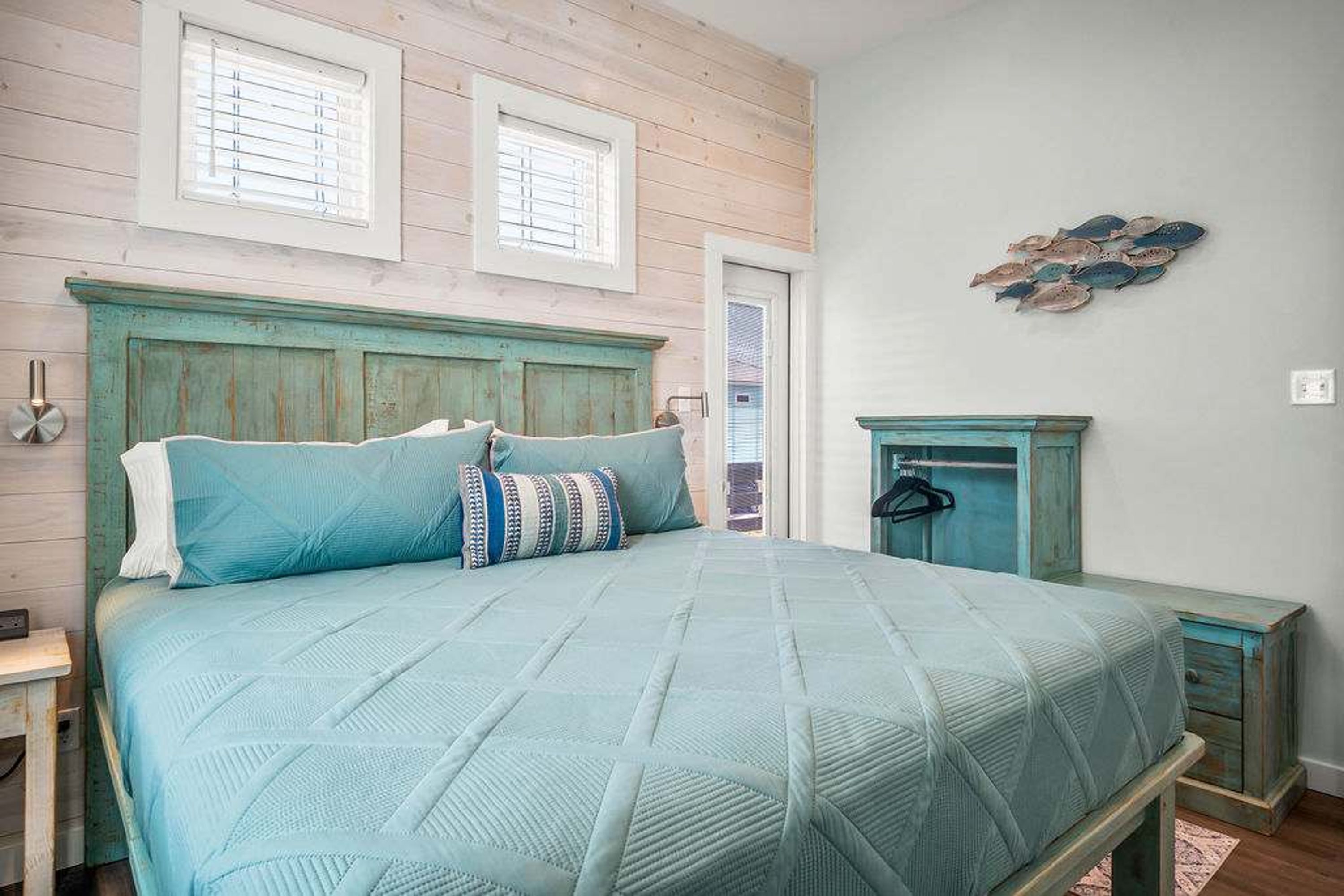A bedroom with a bed, a nightstand, a dresser, and a wall-mounted artwork.