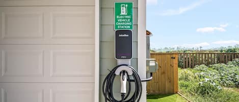 Une borne de recharge pour véhicules électriques fixée à un bâtiment doté d’une porte de garage.