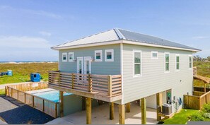 Uma casa à beira-mar com varanda, piscina e vista para o oceano.