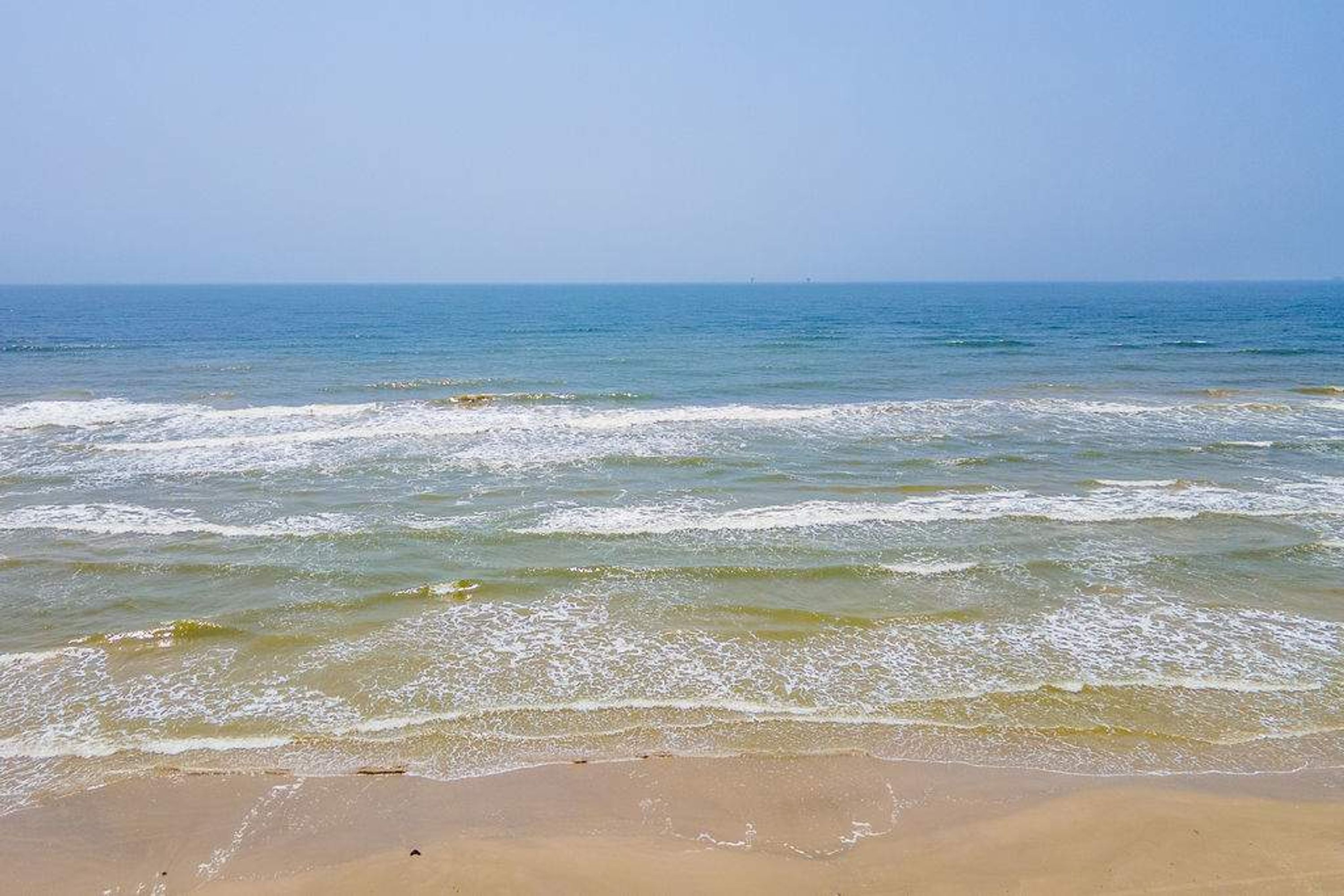 A beach with waves and a clear sky.