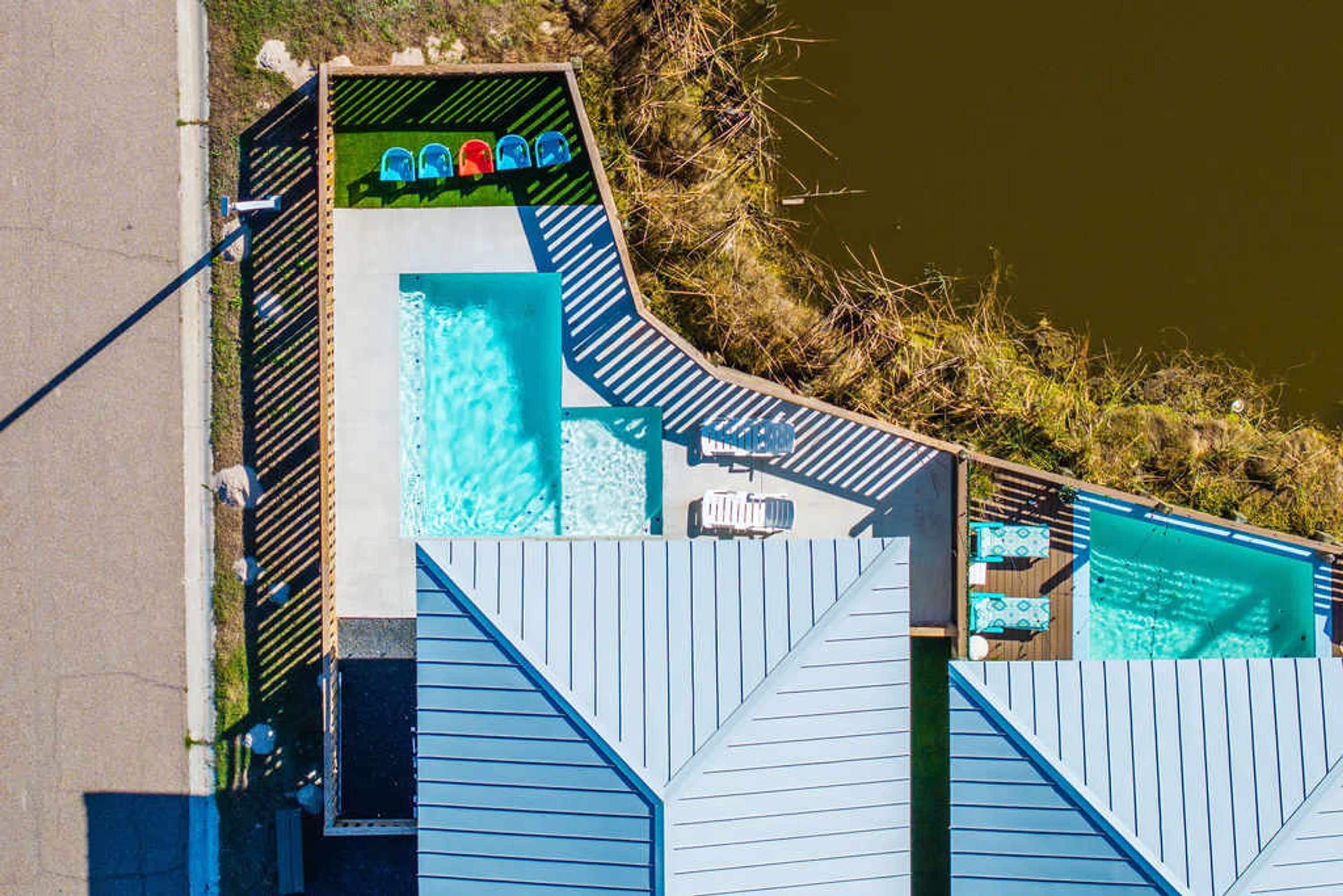 A pool area with multiple swimming pools, a covered seating area with chairs, and a wooden deck.