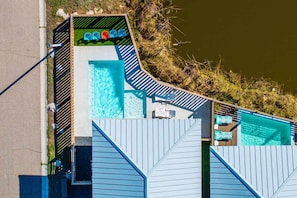 Uma área de piscina com várias piscinas, um espaço de estar coberto com cadeiras e um deck de madeira.