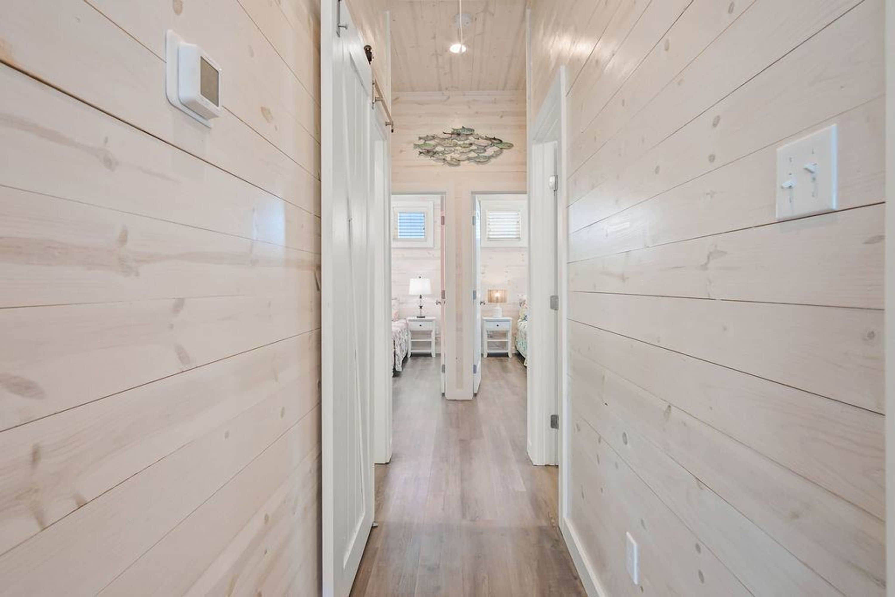 A hallway with wooden walls and a ceiling light fixture.