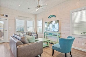 A room with a ceiling fan, a sofa, a coffee table, a chair, and a window with blinds. - Save The Ales Boardwalk Private Pool Sleeps 10 (Port Aransas)